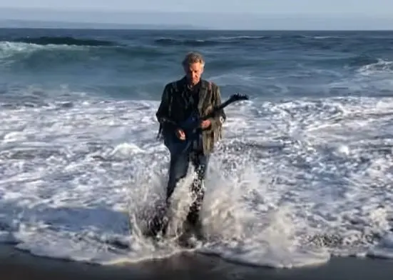 Ole Dammegard playing guitar in the surf